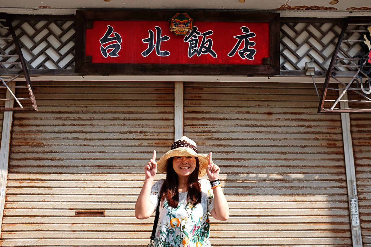 front view, one person, portrait, young adult, outdoors, real people, looking at camera, building exterior, smiling, young women, holding, lifestyles, day, only women, women, leisure activity, built structure, happiness, standing, adult, cheerful, adults only, one woman only, human body part, architecture, one young woman only, people