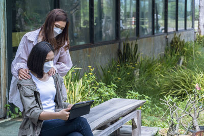 Young woman using mobile phone while sitting on field