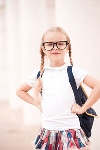 Cute girl with hands on hip standing against wall