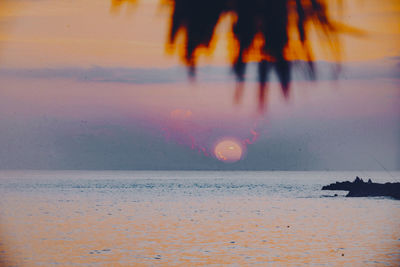Low section of person on beach against sky during sunset