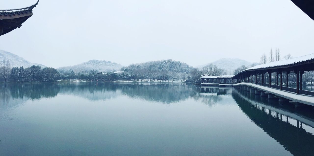 built structure, architecture, reflection, clear sky, water, mountain, lake, waterfront, river, building exterior, mountain range, tranquility, tranquil scene, bridge - man made structure, nature, tree, scenics, standing water, copy space, day