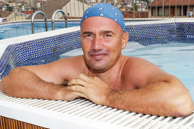 Portrait of shirtless man relaxing in swimming pool