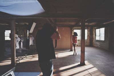 Rear view of man photographing model in studio