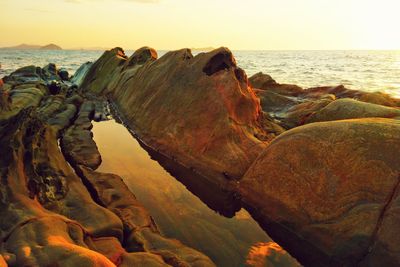 Rock formation on beach against sky