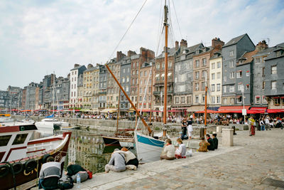 People on street by buildings in city against sky