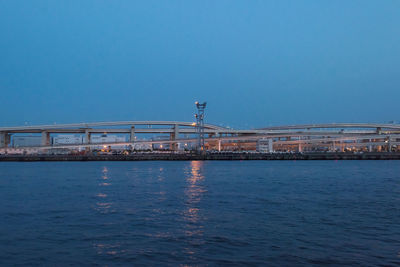 Bridge over sea against clear blue sky