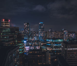 Illuminated buildings in city against sky at night