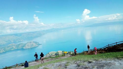 People on mountain by sea against sky