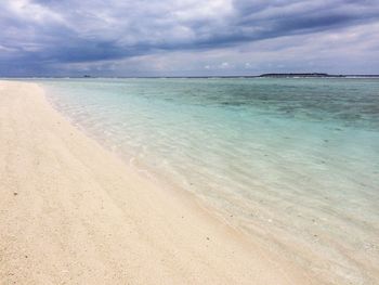 Scenic view of beach against cloudy sky