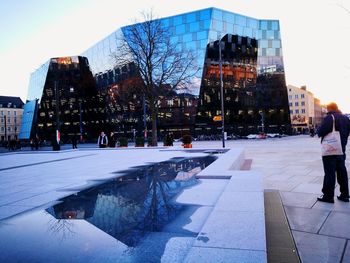 People on street by buildings in city during winter