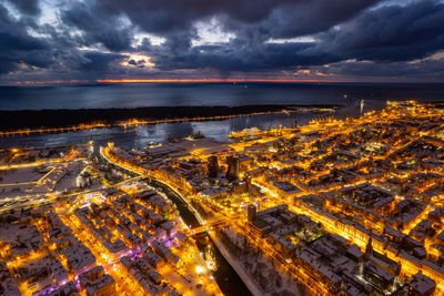 Aerial view of illuminated cityscape against sky at sunset