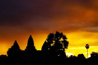 Silhouette trees against orange sky