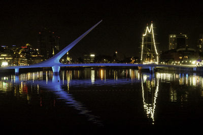 Illuminated bridge over river at night