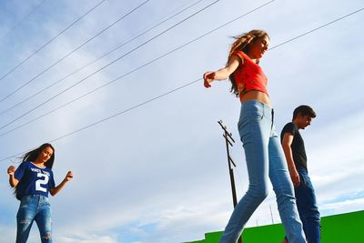 Low angle view of friends standing against sky