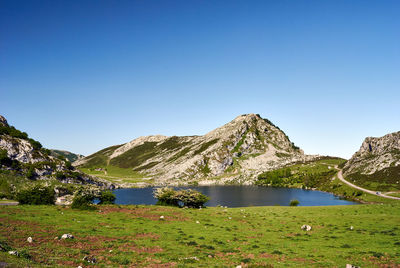 Scenic view of lake and mountains against clear blue sky