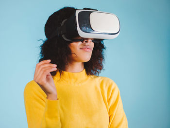 Happy woman using virtual reality simulator against blue background