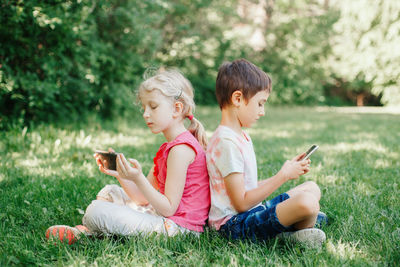 Friends sitting on grass while looking at camera