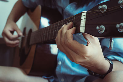 Midsection of man playing guitar