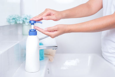 Midsection of person holding hands in bathroom