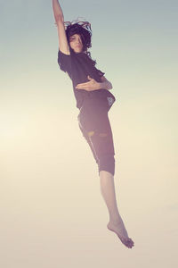 Full length of woman jumping against sky