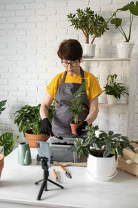 Side view of woman holding potted plant