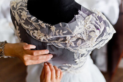 Cropped image of fashion designer adjusting wedding dress on mannequin