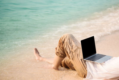 Rear view of woman using mobile phone at beach