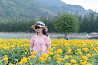 Woman standing on yellow flowers on field