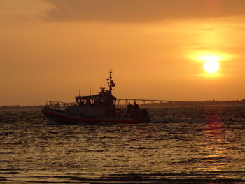 Boat sailing in sea at sunset