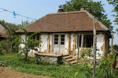 Old house by building against sky