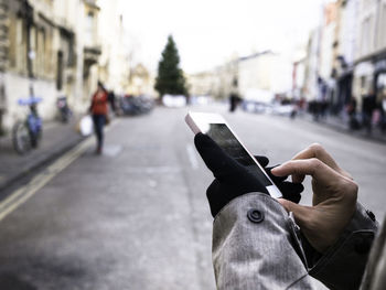 Cropped image of person using phone on city street