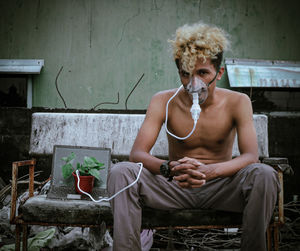 Portrait of young man using mobile phone while sitting at home