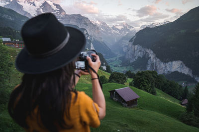 Rear view of woman photographing while standing on field