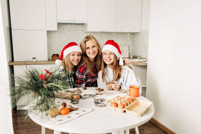 Portrait of a charming mother and her two lovely daughters while making christmas gingerbread