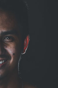 Close-up portrait of young man against black background