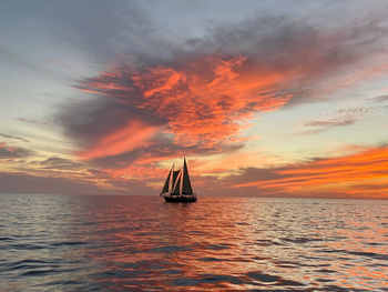 Sailboat in sea against sky during sunset