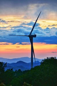 Wind turbines on landscape against sky during sunset