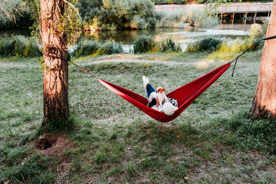 Rear view of woman relaxing with dog on hammock