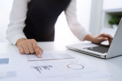 Midsection of businessman using laptop at office