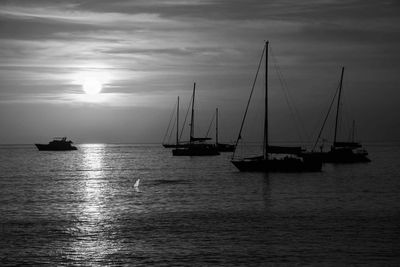 Sailboats sailing in sea against sky during sunset
