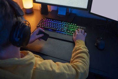 Boy holding credit card while playing video game at home