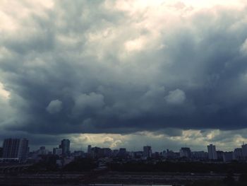 Buildings in city against dramatic sky