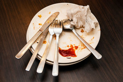 High angle view of dirty plate with cutlery on table