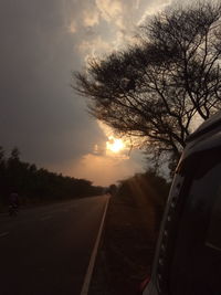 Road amidst trees against sky during sunset