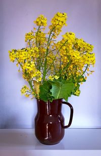 Close-up of flower vase on table against wall