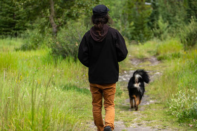 Rear view of man with dog walking on grass