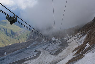 Overhead cable car over snowcapped mountains against sky