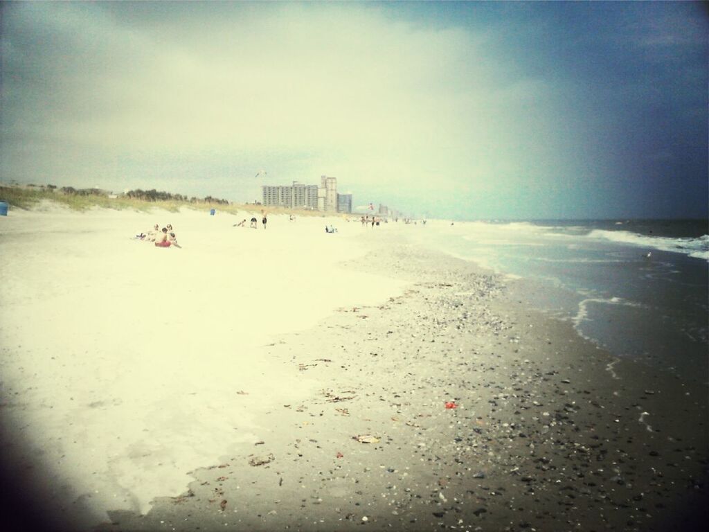 beach, sea, sky, sand, water, architecture, shore, built structure, building exterior, horizon over water, incidental people, cloud - sky, vacations, nature, weather, large group of people, leisure activity, day, lifestyles