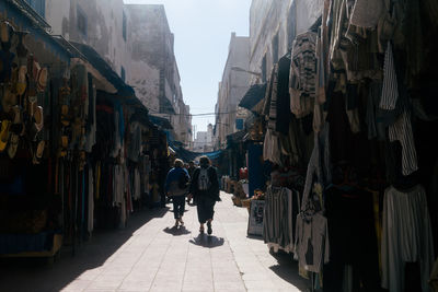 Rear view of people walking on street amidst buildings