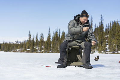 Man ice fishing at sunny day